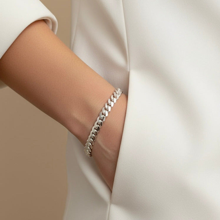 Silver bracelet on a person's wrist with a neutral background