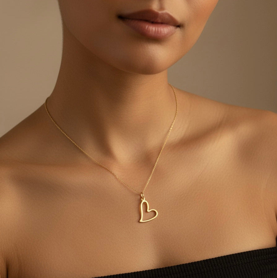 Gold heart necklace on a model against a neutral background