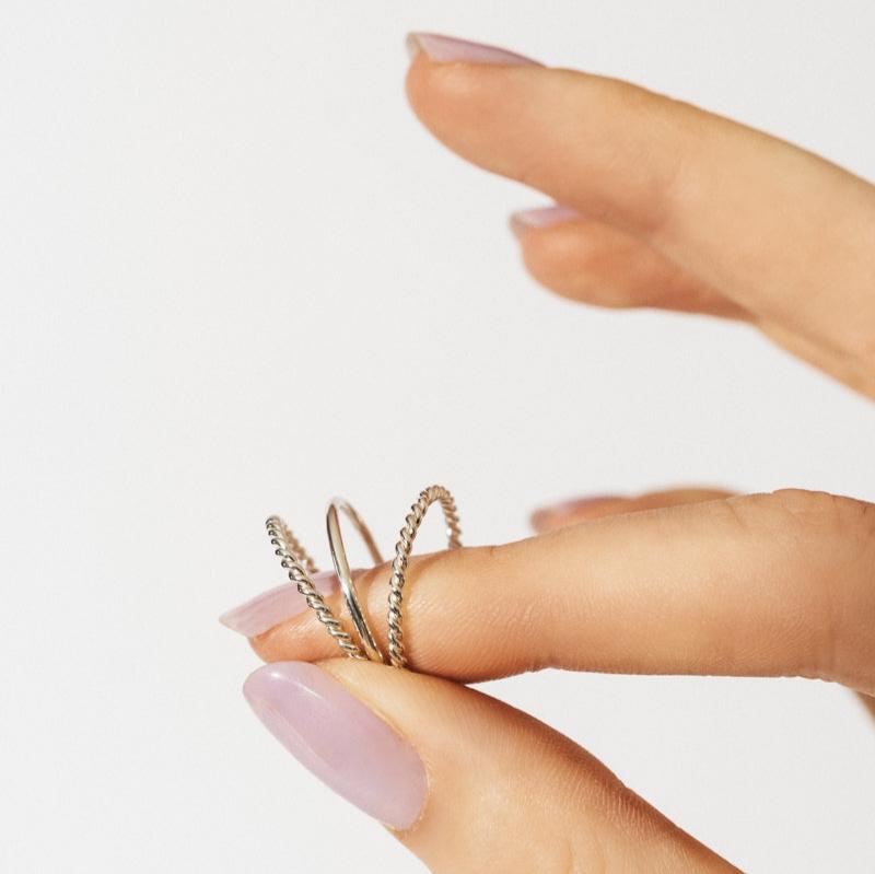 Two delicate Grecia Rings displayed on a finger with stylish nail polish