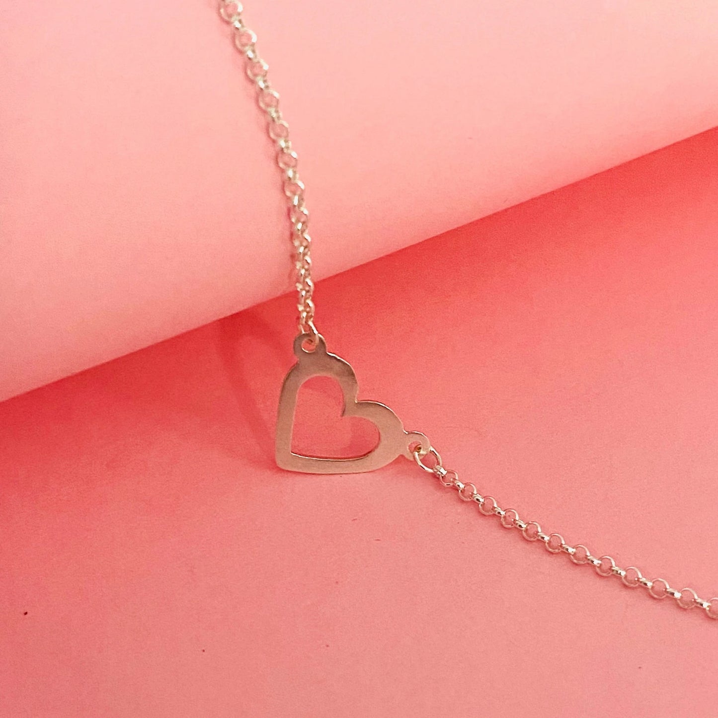 Luisana Jewelry heart bracelet in silver with a delicate open heart design on a pink background