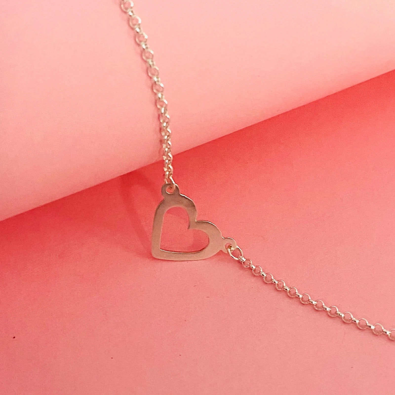Luisana Jewelry heart bracelet in silver with a delicate open heart design on a pink background