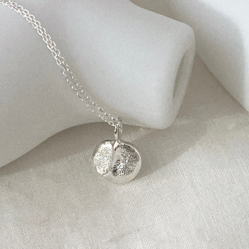 Luisana Jewelry Organic Love Charm Necklace in silver, showcasing a textured round pendant on a delicate chain