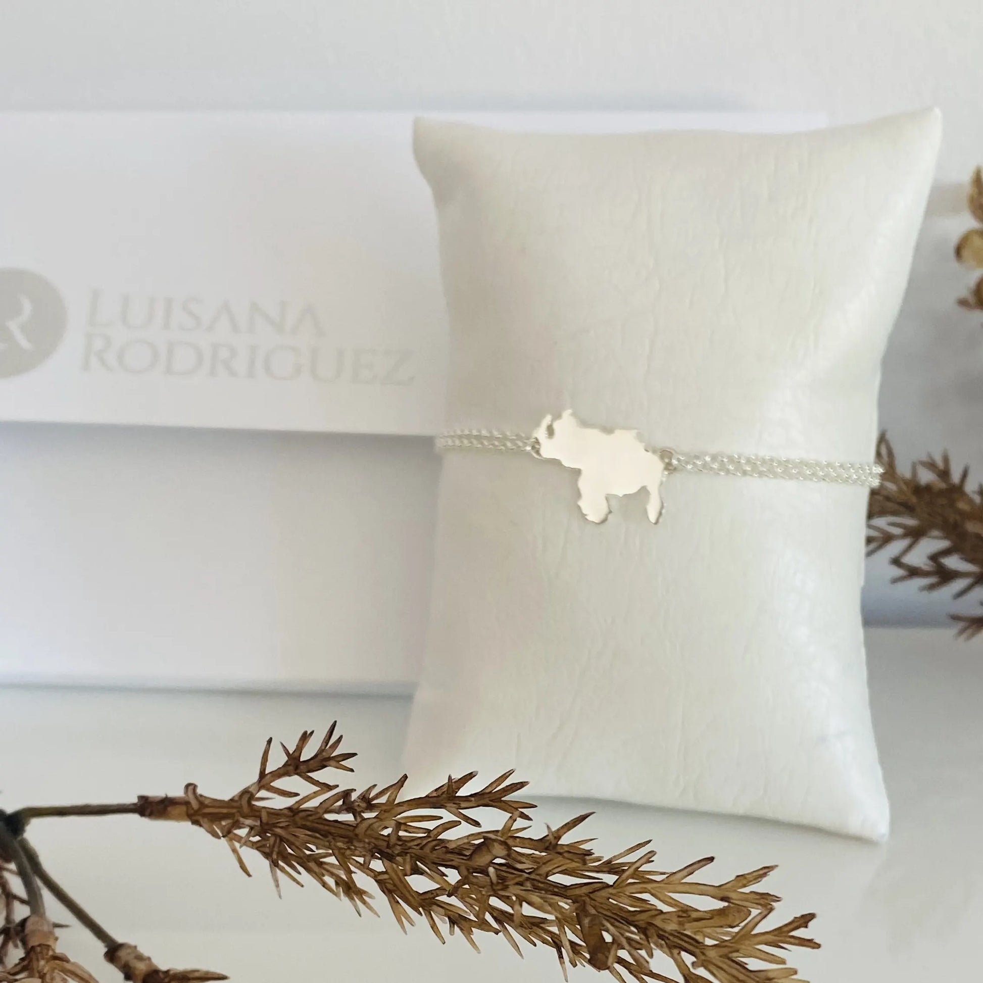 Luisana Jewelry Venezuela bracelet solid with a delicate silver charm on a textured pillow display